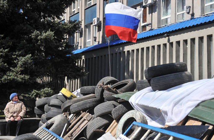 An elderly woman looks at the Russian flag set up by pro-Russian activists at a barricade blocking access to the Ukrainian Security Service building in the eastern Ukrainian city of Lugansk on April 8, 2014.(AFP Photo / Genya Savilov)