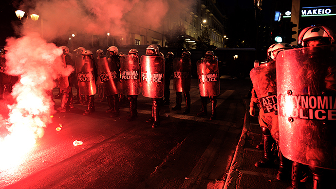 Police advance near red flares left by demonstrators as they clash with anti-austerity protesters and block access to the venue of the European Union Informal Meeting of Ministers for Economic and Financial affairs in Athens on April 1, 2014. (AFP Photo / Louisa Gouliamaki)