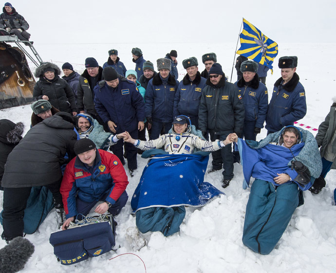 Former ISS commander Oleg Kotov (C) and flight engineers Sergei Ryazansky (L) and Michael Hopkins from NASA sit in chairs outside the Soyuz TMA-10M capsule shortly after they landed in a remote area southeast of the town of Zhezkazgan in central Kazakhstan, March 11, 2014. (Reuters/Bill Ingalls/NASA)