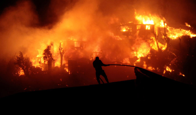 A firefighter works near houses on fire in Valparaiso, 110 km west of Santiago, Chile, on April 12, 2014. (AFP Photo/Felipe Gamboa)