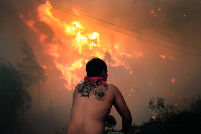 A local stares at houses in flames during a fire in Valparaiso, 110 km west of Santiago, Chile, on April 12, 2014. (AFP Photo/Felipe Gamboa)