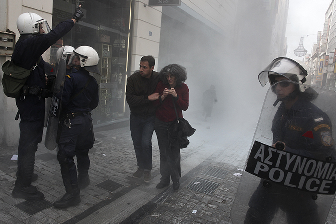 People walk from tear gas during scuffles between police and protesters demonstrating against the government's decision to allow shops to open for more than two Sundays a year, in the commercial Ermou Street in central Athens April 13, 2014. (Reuters / Alkis Konstantinidis)