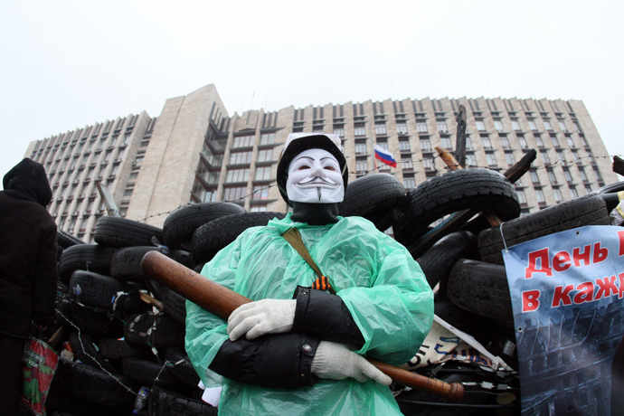 A pro-Russian activist wearing a Guy Fawkes mask and holding a bat guards a barricade outside the regional government building in the eastern Ukrainian city of Donetsk on April 13, 2014 (AFP Photo / Alexander Khudoteply)