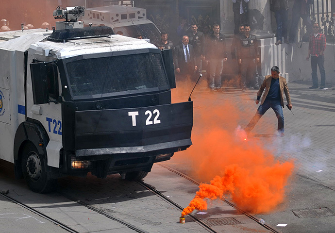 A smoke flare is seen in front of a police vehicle as Galatasaray, Fenerbahce and Besiktas clashed with riot police during a protest against a new system of e-tickets on April 20, 2014, on Istiklal Avenue in Istanbul. (AFP Photo / Ozan Kose)