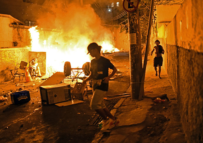 Residents run for cover during violent clashes between protestors and Brazilian Police Special Forces in a favela near Copacabana in Rio de Janeiro, Brazil on April 22, 2014. (AFP Photo / Christophe Simon)