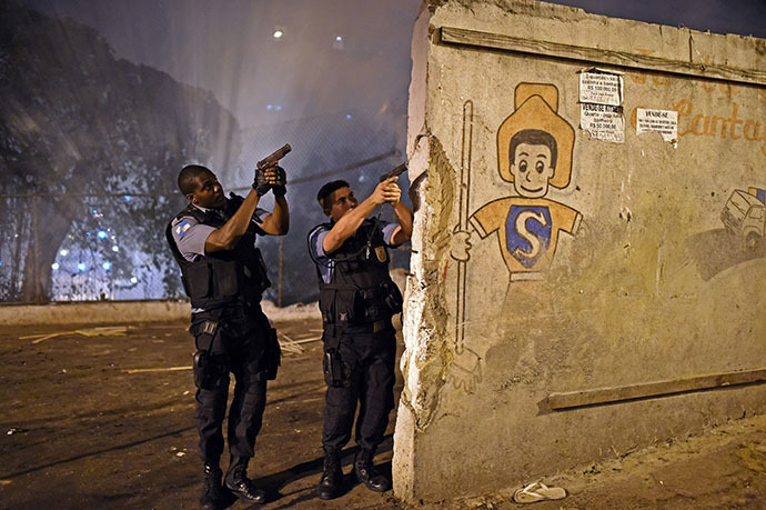 Rio de Janeiro's state military policemen aim their guns during a violent protest in a favela next to Copacabana, Rio de Janeiro on April 22, 2014. (AFP Photo / Christophe Simon)