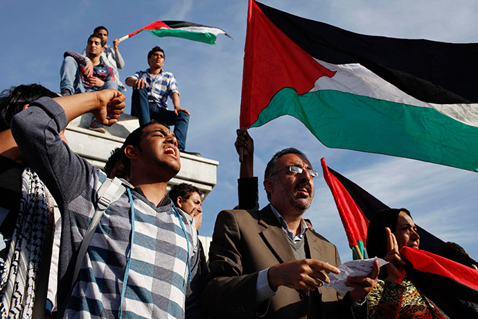 Palestinians wave national flags as they celebrate after an announcement of a reconciliation agreement in Gaza City April 23, 2014 (Reuters / Ibraheem Abu Mustafa)