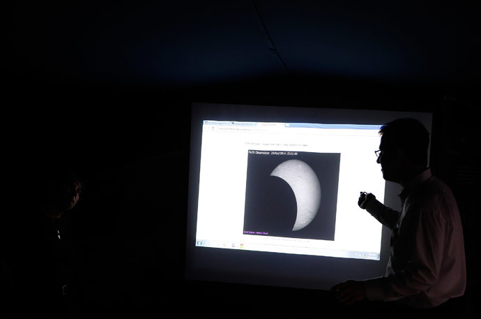 A man talks to a visitor in front of a screen displaying the partial solar eclipse as seen from the city of Perth during a gathering of amateur astronomers at Sydney's Observatory Hill April 29, 2014. (Reuters / David Gray)