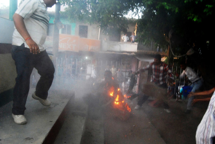 Indian bystanders attempt to douse the blaze during an election television debate in a local park in Sultanpur. (AFP Photo)