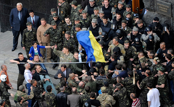 A handout picture released on April 30, 2014 by Ukrainian Prime Minister Press Office shows Maidan self-defence activists fighting with police special team guarding the Ukrainian Cabinet of the Ministers as a man holds an Ukrainian national flag in Kiev on April 30, 2014 (AFP Photo / Andrey Krafchenko)