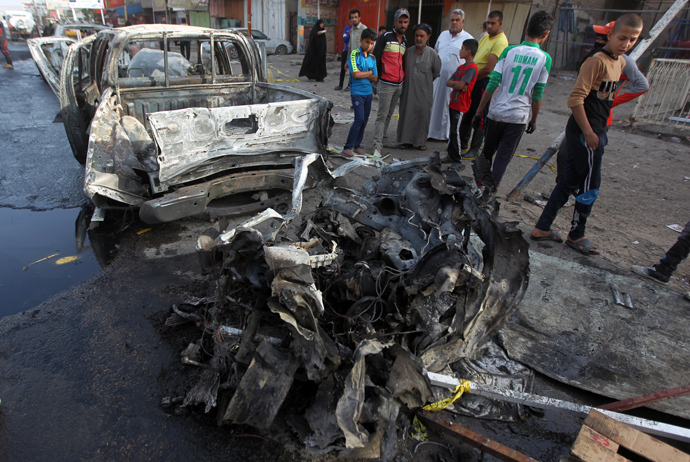 Iraqi citizens inspect destruction in the street following an explosion the previous day in Baghdad's northern Shiite-majority district of Sadr City on April 17, 2014 (AFP Photo)