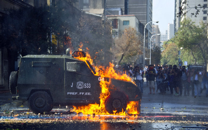 A riot police armored car is hit by a molotov cocktail thrown by students during a protest against the education system on May 8, 2014 in Santiago. (AFP Photo)