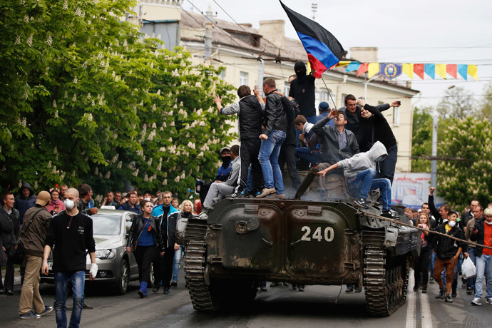 People climb an armored vehicle captured after Ukrainian forces attacked police headquarters in Mariupol. May 9, 2014.(Reuters / Marko Djurica)