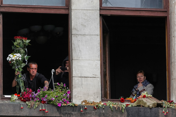 Local residents lay flowers at broken windows of a burnt trade union building before an Orthodox ceremony to mourn the deaths of pro-Russian supporters killed last week during street battles between pro-Russian and pro-Ukrainian supporters, in the Black Sea port of Odessa May 10, 2014 (Reuters / Yevgeny Volokin)