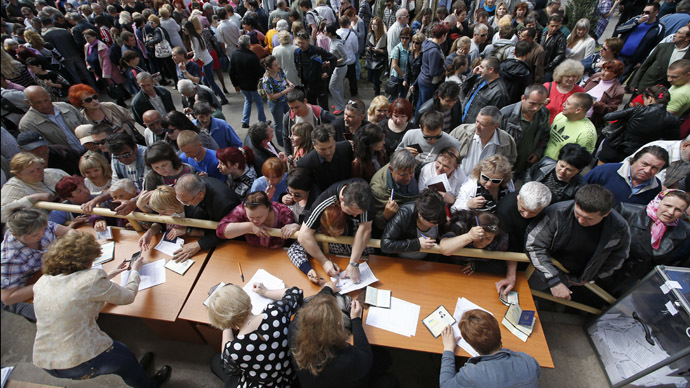 People stand in a line to receive ballots from members (front) of a local election commission during the referendum on the status of Donetsk region in the eastern Ukrainian city of Mariupol May 11, 2014. (Reuters/Marko Djurica)