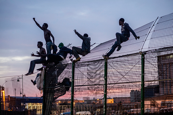 Would-be immigrants react on a fence into the north African Spanish enclave of Melilla on March 28, 2014 after an attempt of dawn assault to cross into the Spanish city, which lies on the northern tip of Morocco (AFP Photo / Jose Colon)