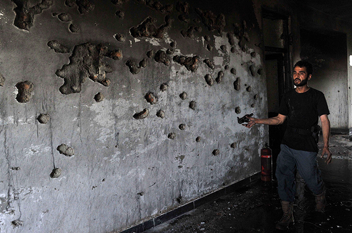 An Afghan policeman displays shrapnel at the site of a suicide attack in Jalalabad province on May 12, 2014 (AFP Photo / Noorullah Shirzada)