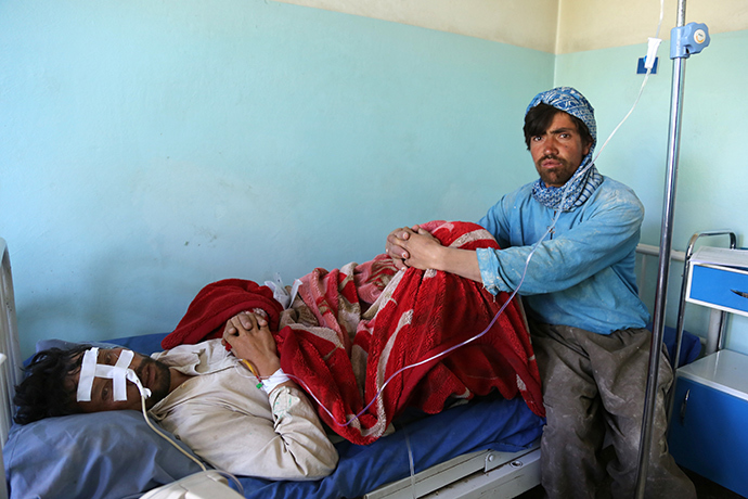 A wounded Afghan patient (L) rests in a hospital bed as a companion looks on following an attack in Ghazni province on May 12, 2014 (AFP Photo)
