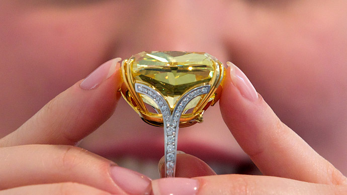 A Sotheby's employee poses for pictures with the "Graff Vivid Yellow," at 100.09 carats, one of the rarest yellow diamonds of its size, in London on April 11, 2014. (AFP Photo/Andrew Cowie)