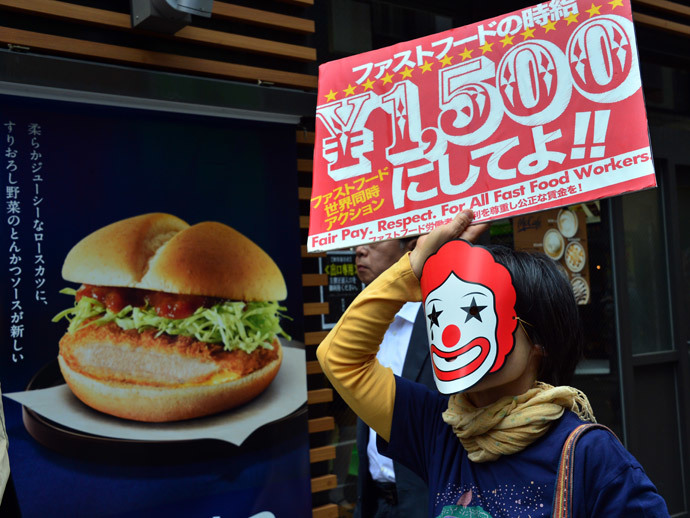 A labour union member holds a placard to demand payment of 1,500 yen (15 USD) an hour for a part-time job at a McDonald's fast-food restaurant in Tokyo on May 15, 2014.(AFP Photo / Yoshikazu Tsuno)