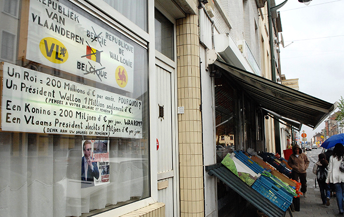 Pedestrians walk on the pavement, 14 May 2007, a few meters next of two billboards pasted on a shopwindow by a local resident of Ninovse Steenweg, Sint-Jans-Molenbeek / Chaussee de Ninove, Molenbeek-Saint-Jean, expressing his opinion in favour of two republics ie Flanders and Wallonia, instead of the Belgium monarchy (AFP Photo / Herwig Vergult)