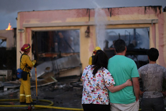 Residents looks at the burning remains of their home that was destroyed in the Poinsettia fire, one of nine wildfires fueled by wind and record temperatures that erupted in San Diego County throughout the day, on May 14, 2014 in Carlsbad, California. (AFP Photo / David Mcnew)