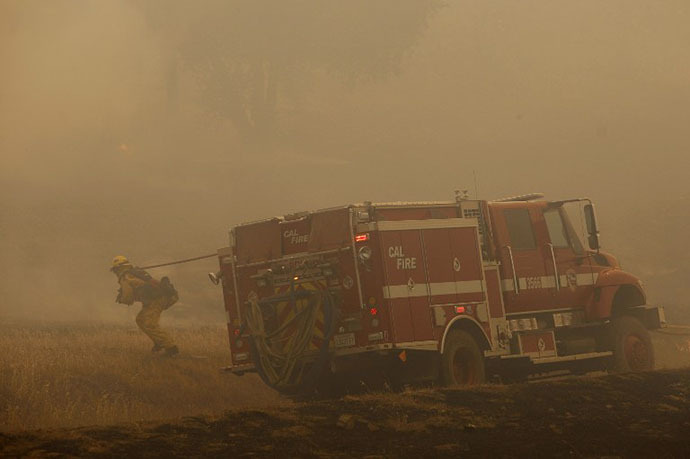 A firefighter pulls a hose into position to battle the Cocos fire on May 15, 2014 in San Marcos, California. (AFP Photo / David Mcnew)