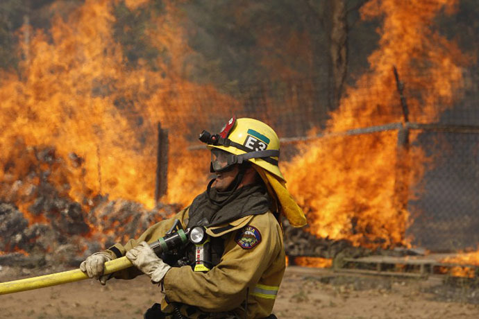 A firefighter pulls a hose in position while battling the Cocos fire on May 15, 2014 in San Marcos, California. (AFP Photo / David Mcnew)
