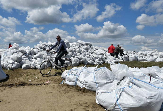 A man rides a bicycle among sand bags protecting the banks of the Sava river in the Serbian city of Sremska Mitrovica, 70 kilometers west of Belgrade, on May 18, 2014. (AFP Photo / Andrej Isakovic)