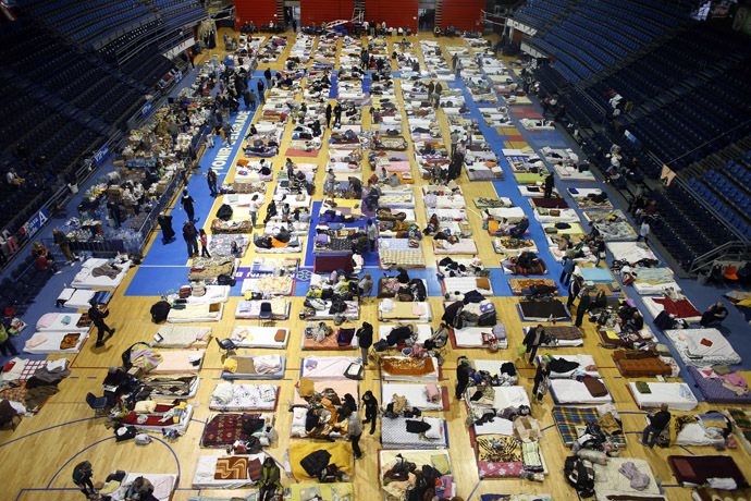 Evacuees from the Serbian town of Obrenovac are seen lying on beds in a shelter hall in Belgrade, May 18, 2014. (Reuters/Marko Djurica)