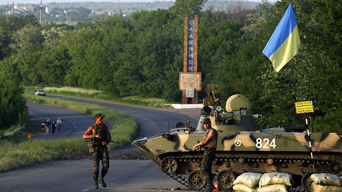 Ukrainian army servicemen stand near an armoured fighting vehicle as they man a checkpoint in the outskirts of Slaviansk (Reuters / Yannis Behrakis)