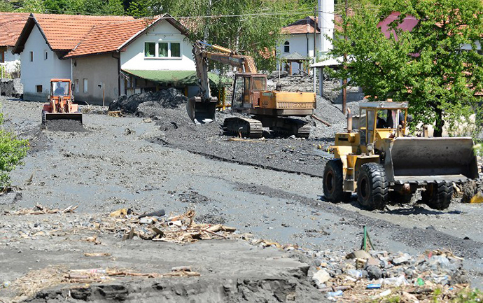 Workers use a backhoe and bulldozers to clear the earth after a landslide in the flooded village of Topcic Polje, near the northern Bosnian city of Doboj, on May 19, 2014 (AFP Photo / Elvis Barukcic)