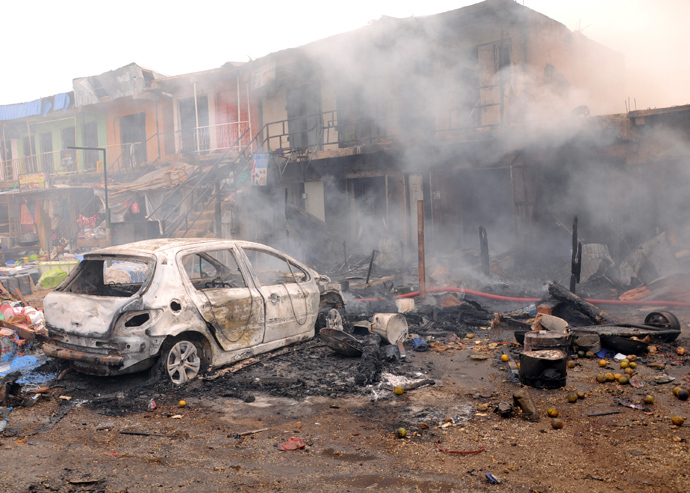The wreckage of a burnt vehicle remains in front of burning shops following a bomb blast at Terminus market in the central city of Jos on May 20, 2014 (AFP Photo / STR)