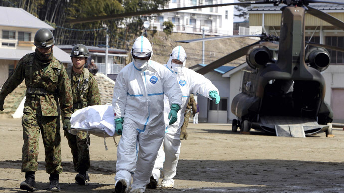 A person, who is believed to be have been contaminated with radiation, in a white bag is carried by soldiers at a radiation treatment centre in Nihonmatsu city in Fukushima prefecture on March 13, 2011. (AFP Photo)