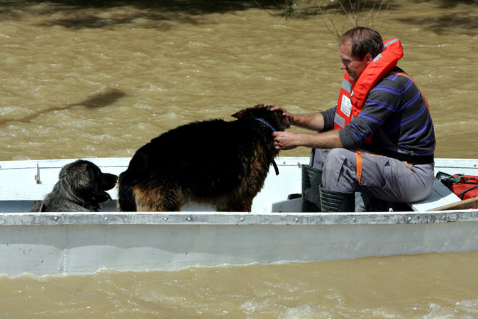 A Croatian rescuer with two dogs in a boat on a flooded street in the village of Gunja, in eastern Croatia, 18 May, 2014. (AFP Photo)