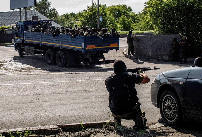 An anti-government fighter takes position behind a car as a truck full of self-defense forces heads towards the battle during clashes against Ukrainian forces near the airport in Donetsk on May 26, 2014. (AFP Photo / Fabio Bucciarelli)