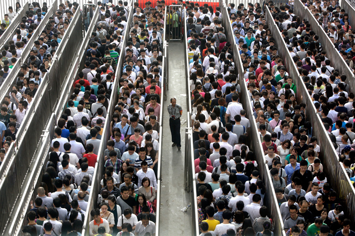 A security officer stands guard as passengers line up and wait for a security check during morning rush hour at Tiantongyuan North Station in Beijing May 27, 2014 (Reuters / Jason Lee)