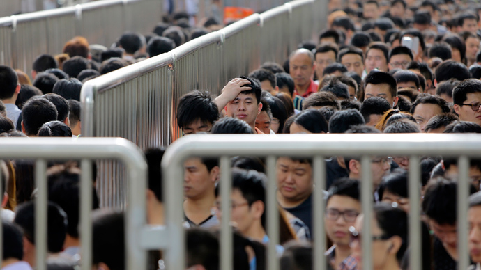 A man looks up as he lines up with other passengers and waits for a security check during morning rush hour at Tiantongyuan North Station in Beijing May 27, 2014 (Reuters / Jason Lee)