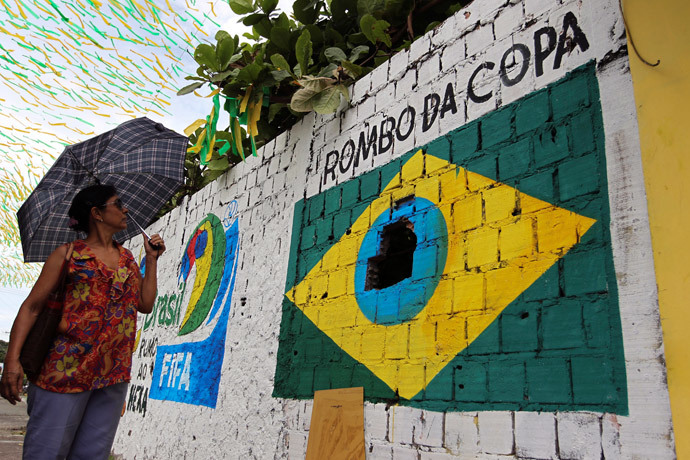 A pedestrian looks at a graffiti in protest against the 2014 World Cup that shows the Brazilian flag painted around a hole in a wall in Manaus, one of the host cities, May 23, 2014. (Reuters / Bruno Kelly)