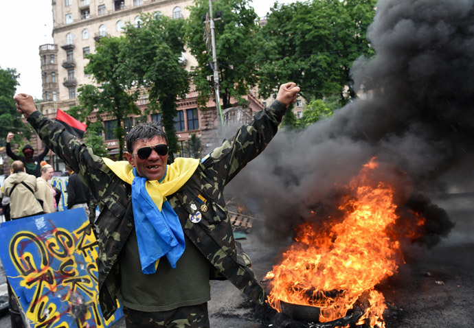 A protester from Kiev's Independence Square, the so-called "Maidan", gestures as fellow protesters burn tyres to protect their barricades from being dismantled by communal services on May 31, 2014 in the centre of Kiev.(AFP Photo / Sergei Supinsky )