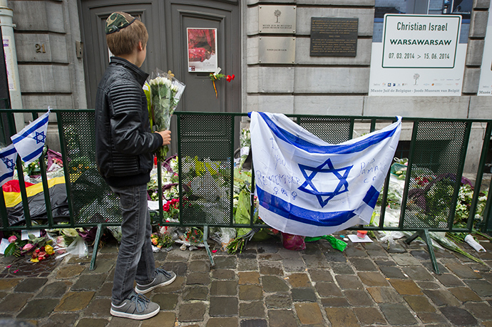 A Jewish boy stands with flowers in front of an Israeli flag and flowers laid in front of the Jewish Museum in Brussels on May 26, 2014 (AFP Photo)