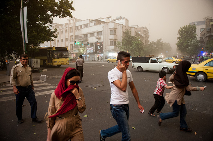 Iranians walk amidst dust as a sandstorm engulfs the capital Tehran on June 02, 2014. (AFP Photo / ISNA / Hamidreza Dastjerdi)