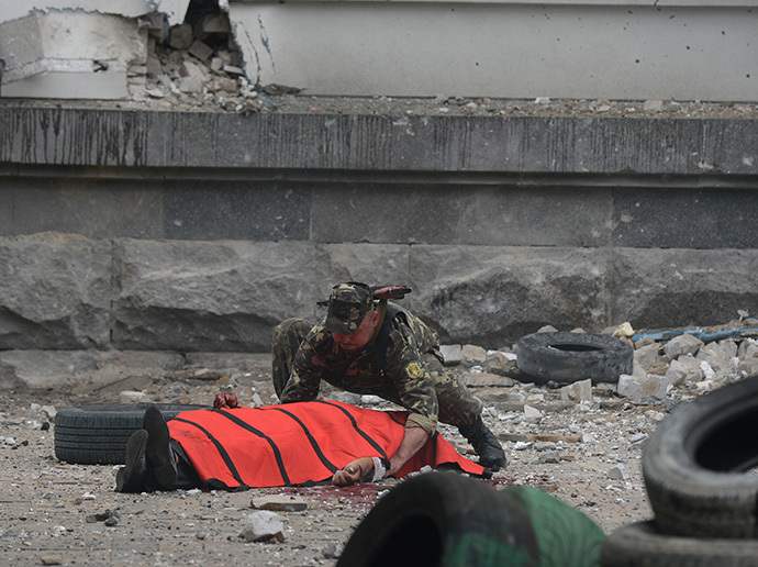 A member of the local self-defense forces covers the body of a person killed during the air attack on the building of Lugansk regional administration by Ukrainian air force. (RIA Novosti / Evgeny Biyatov)