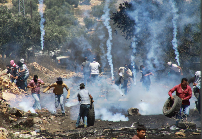 Palestinian protesters run away from tear gas fired by Israeli soldiers during clashes following a protest against the Jewish settlement of Qadomem, in the West Bank village of Kofr Qadom near Nablus May 23, 2014. (Reuters / Abed Omar Qusini)