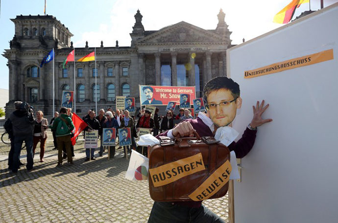 An activist wearing a mask of fugitive US intelligence leaker Edward Snowden tries to get past a door reading "Investigation Committee" while holding a suitcase reading "Evidence" during a demonstration in favor of an appearance by Snowden as a witness in German NSA hearings held in the German Bundestag, or lower house of parliament, outside the Reichstag building in Berlin on May 8, 2014. (AFP Photo / Adam Berry)