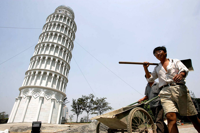 Chinese workers walk past a 1:4 scale mini leaning tower of Pisa in Shanghai (Reuters / China Photos ASW / TW)