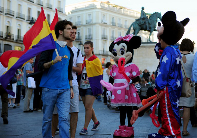 Protesters holding flags of the Spanish Second Republic walk past people dressed up as cartoon characters during a demonstration to demand a referendum on the monarchy following the abdication of King Juan Carlos, in Madrid on June 7, 2014. (AFP Photo / Tom Gandolfini)