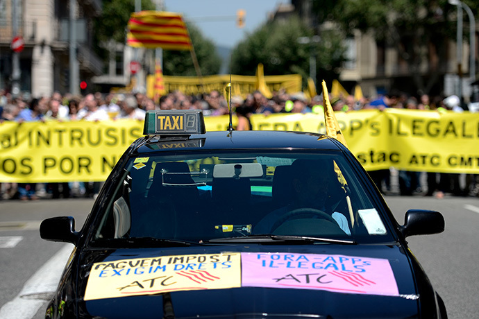 A taxi preceeds demonstrators holding a banner during a strike action in protest of unliscensed taxi-type-services in Barcelona on June 11, 2014. (AFP Photo / Josep Lago)