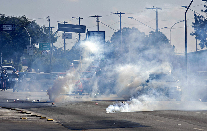 Tear gas grenades explode among cars during an anti-World Cup protest, on the morning the Brazilian mega-city hosts the tournament's opening match, in Sao Paulo on June 12, 2014. (AFP Photo / Miguel Schincariol)