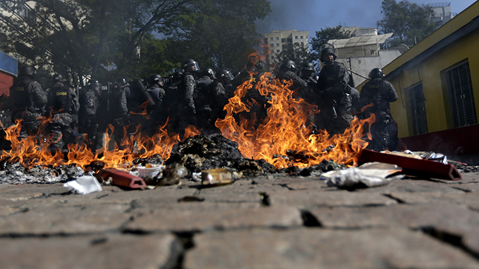 Riot policemen stand behind burning rubbish during a protest against the 2014 World Cup in Sao Paulo June 12, 2014. (Reuters / Ricardo Moraes)